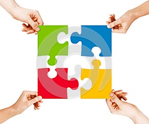 Four hands connecting puzzle pieces