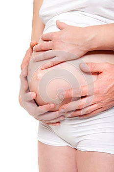 Four hands holding belly of a pregnant woman