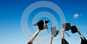 Four hands holding graduation hats against sky photo