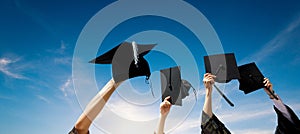 Four hands holding graduation hats against sky photo