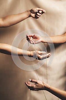 Four hands joined and connected through a thread.