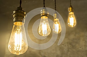 Four hanging light bulbs over oxide dark color concrete background