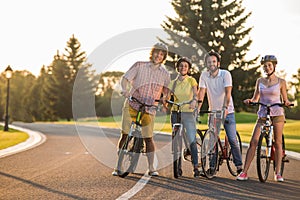 Four happy friends on bikes outdoors.