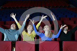 Four happy friends sit in cinema theater