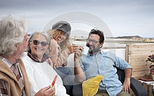 Four happy people together, senior and middle-aged people having fun eating and drinking outdoors on the terrace - couples