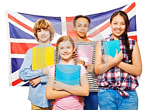 Four happy students standing against British flag