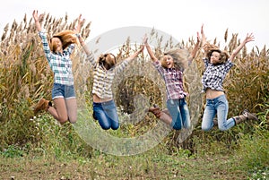 Four happy teenage friends outdoors jumping