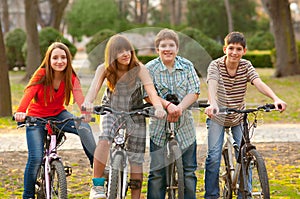 Four happy teenage friends riding bicycles