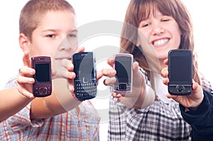 Four happy teenagers showing their cellphones