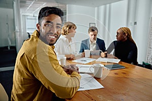 Four happy young multiracial adults in businesswear talking in meeting room at office photo