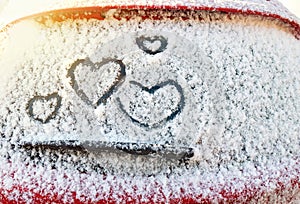 Four hearts symbol of love hand drawing painted on snow on the glass above windshield wiper of car. Valentines day, love.