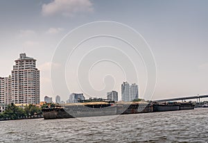 Four heavy barges anchored in Chao Phraya River, Bangkok Thailand