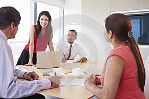 Four Hispanic Businesspeople Having Meeting In Boardroom