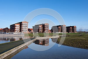 Four identical modern red brick apartment buildings standing close to a lake in Lund Sweden