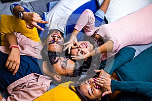 Four indian friends lying down on the floor with pillows