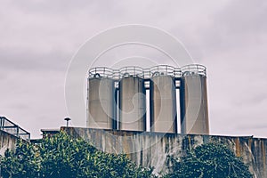 Four industrial metal storage tanks above a wall