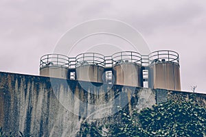 Four industrial metal storage tanks above a wall