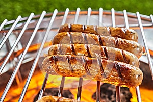 Four juicy pork sausages grilling on a BBQ