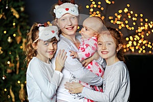 Four kids girls cuddling on Christmas Eve. The concept of Merry Christmas, holidays, family and gifts