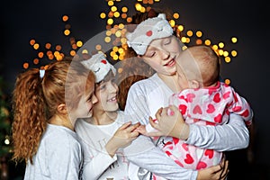 Four kids girls cuddling on Christmas Eve. Sisters in pajamas. The concept of Merry Christmas, holidays, family and gifts