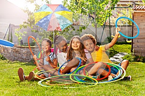 Four kids in a group sit with hula hoops on lawn