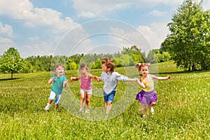 Four kids holding hands and standing together