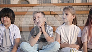 Four kids looking bored and overtired seating on a bench. photo