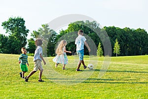 Four kids are playing on evening glade.