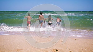 Four kids running to the sea from the beach