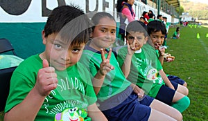 Four kids salutes to the camera in a sport event in mexico