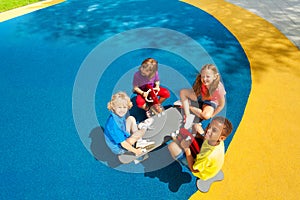 Four kids sitting on carousel view from top