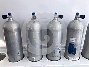Four large metal, aluminum oxygen bottles for breathing, diving with valves, gearboxes stand on special stands on board a boat, sh