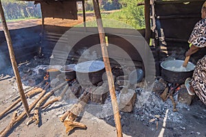 Four large saucepans resting on log fires