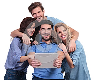 Four laughing casual people reading on a tablet pad computer