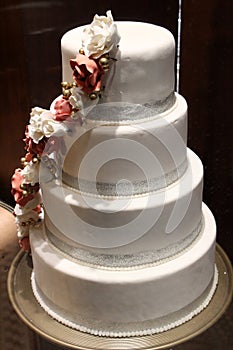 Four layer cake decorated with white frosting and sweep of candy flowers