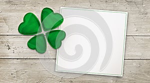 Four leaf clover and greeting card on wood