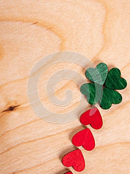 A four-leaf clover made of green hearts with a red stem is laid out on