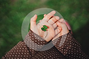 Four leaf green clover in small child`s hands of happy young bab