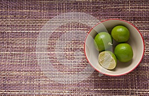 Four limes in a cup on mat background