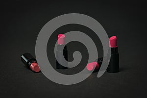 Four lipstick samples on a black background.