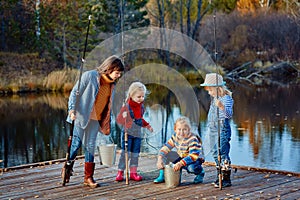 Four little girls catch fish on a wooden pontoon.Weekend at the lake. Fishing with friends.