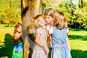 Four little girls playing and whispering in the park