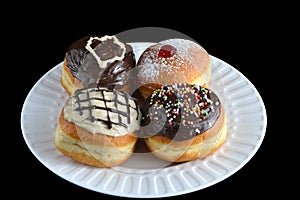 Four luxury sufganiyot with different icing on a white plate