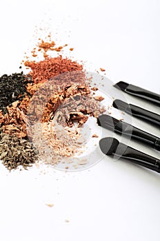 Four makeup brushes and crumbled eyeshadows of different colors