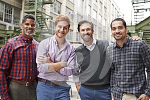 Four male coworkers smiling to camera outside