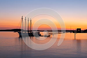 Four-mast sailboat anchored at the pier in Frenchman Bay during a pink and orange sunrise