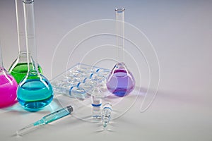 Four medical flasks with colorful chemical reagents. Seven mockup ampoules with transparent liquid and syringe isolated