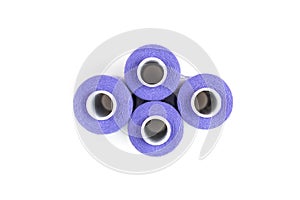 Four medium purple sewing threads on a white coils on a white background. Sewing supplies