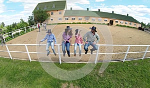 Four members family sit on fence near stable of photo