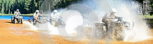 Four Men driving motocross ATV quad through splashing river lake water with high speed. Foy, Foyross Lake, Sudbury